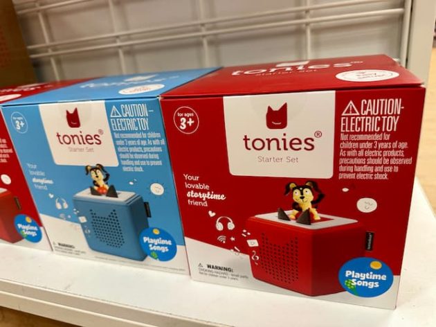 Shelf display of Tonies Starter Sets in red and blue packaging, each featuring a small audio box toy with a cartoon dog figure on top.